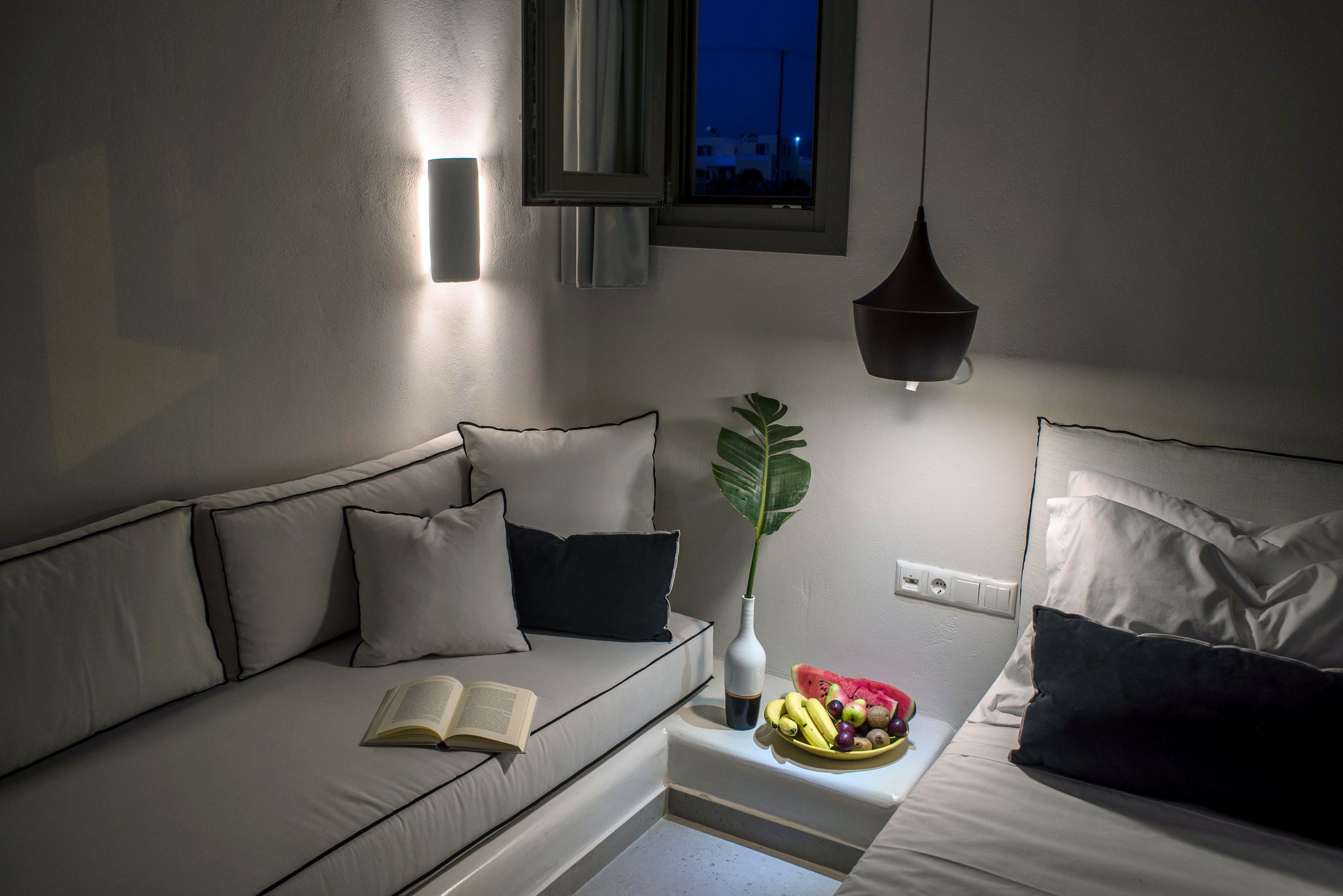 A modern bedroom with a sofa, bedside table, and a bed.