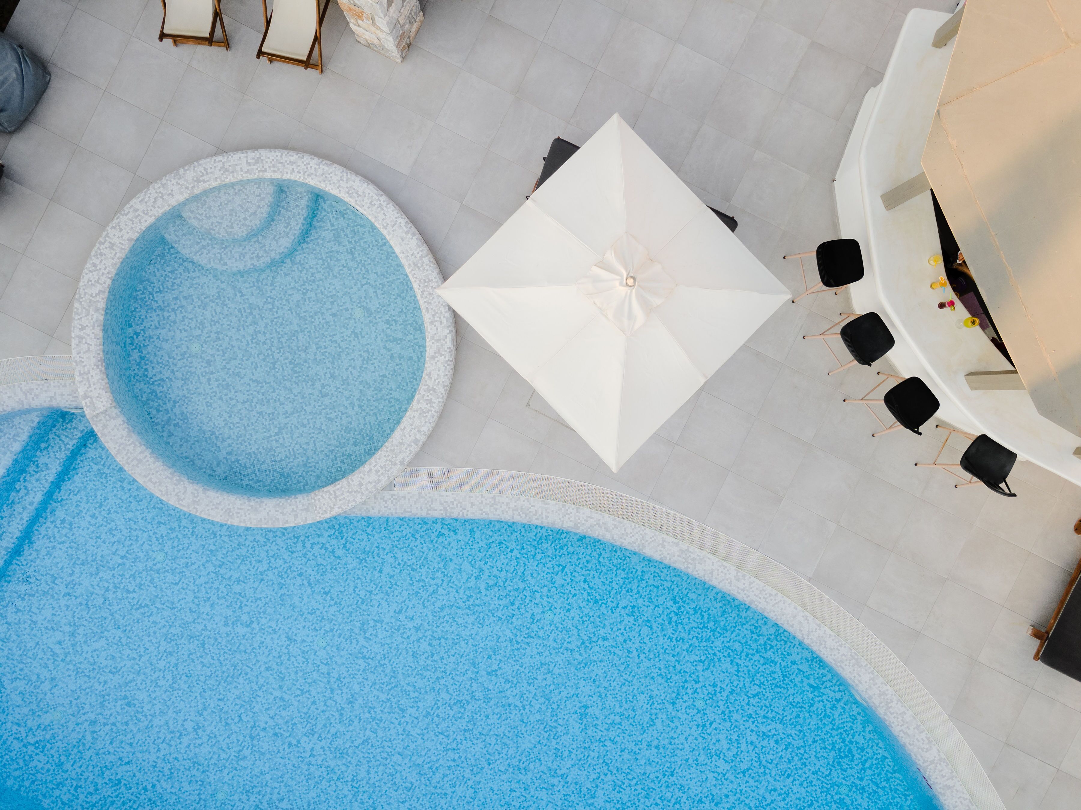 A rooftop pool area with a hot tub, a covered seating area, and a lounge with chairs.