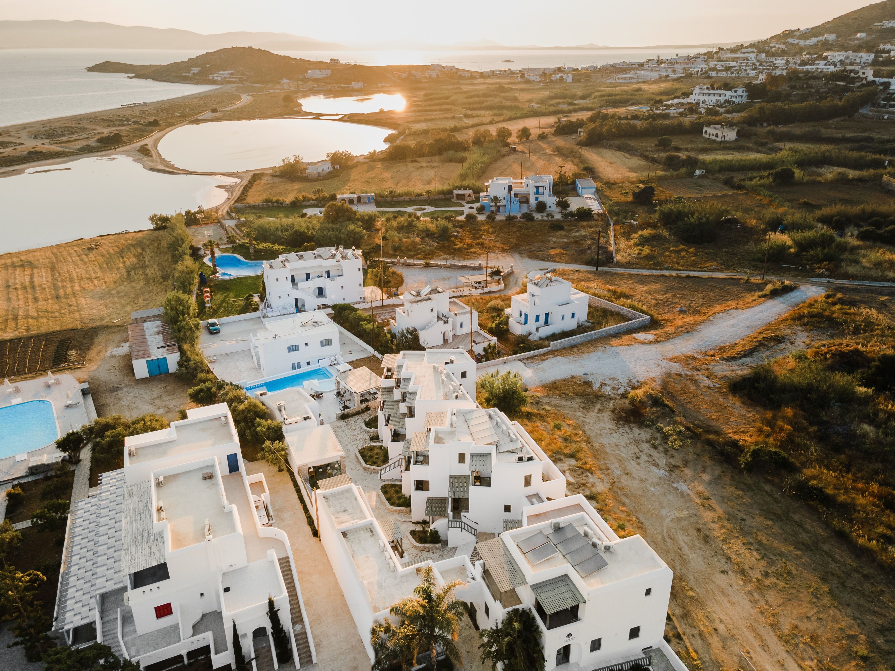 A coastal village with white buildings, a swimming pool, and a view of the sea.