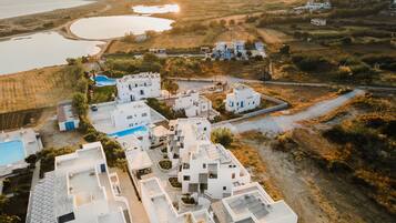A coastal village with white buildings, a swimming pool, and a view of the sea.