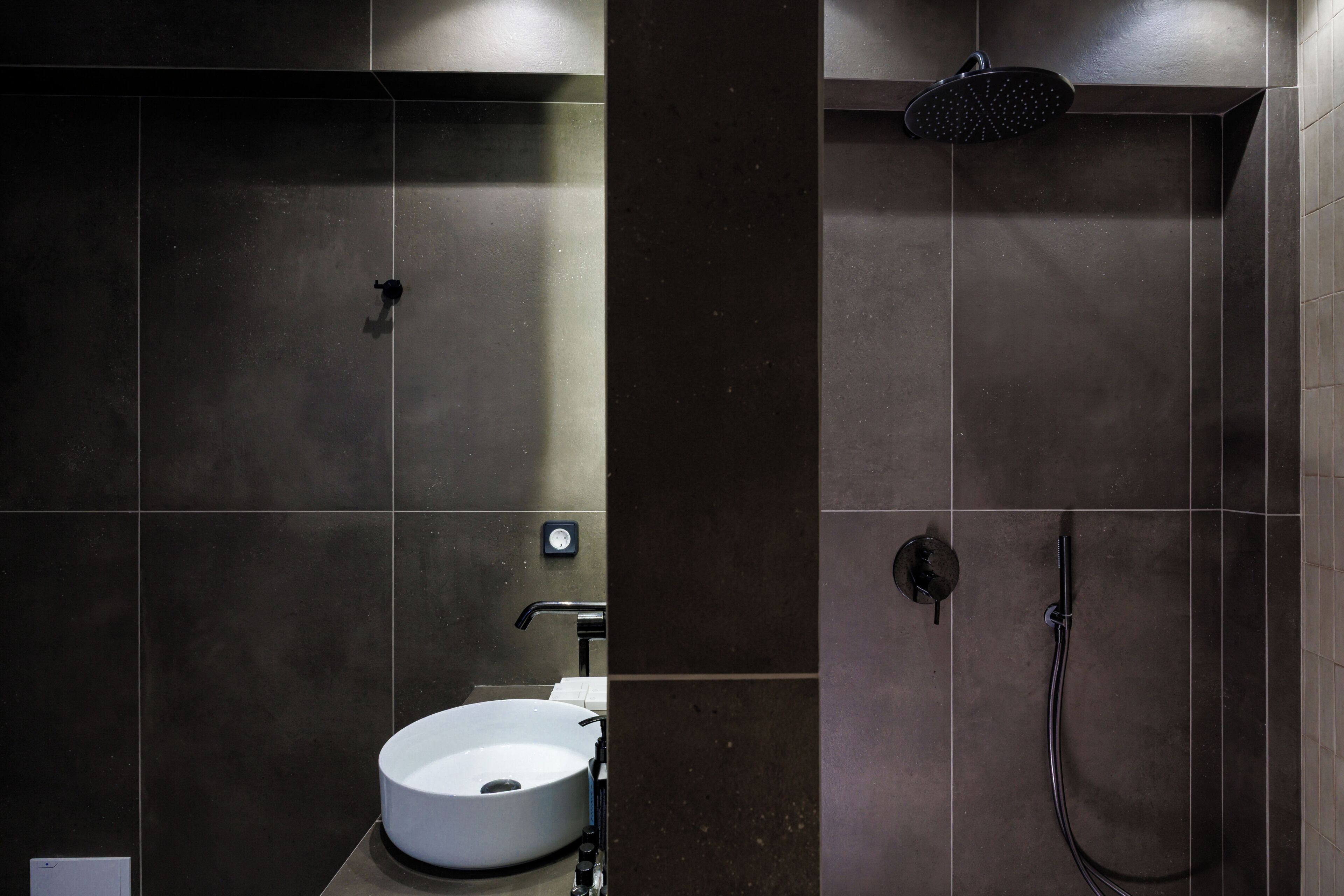 Une salle de bain moderne avec un lavabo rond, une douchette à main et un robinet mural.