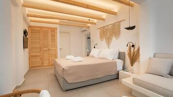 A modern bedroom with a bed, a sofa, and a coffee table. There is a wooden ceiling and a wall-mounted lamp.
