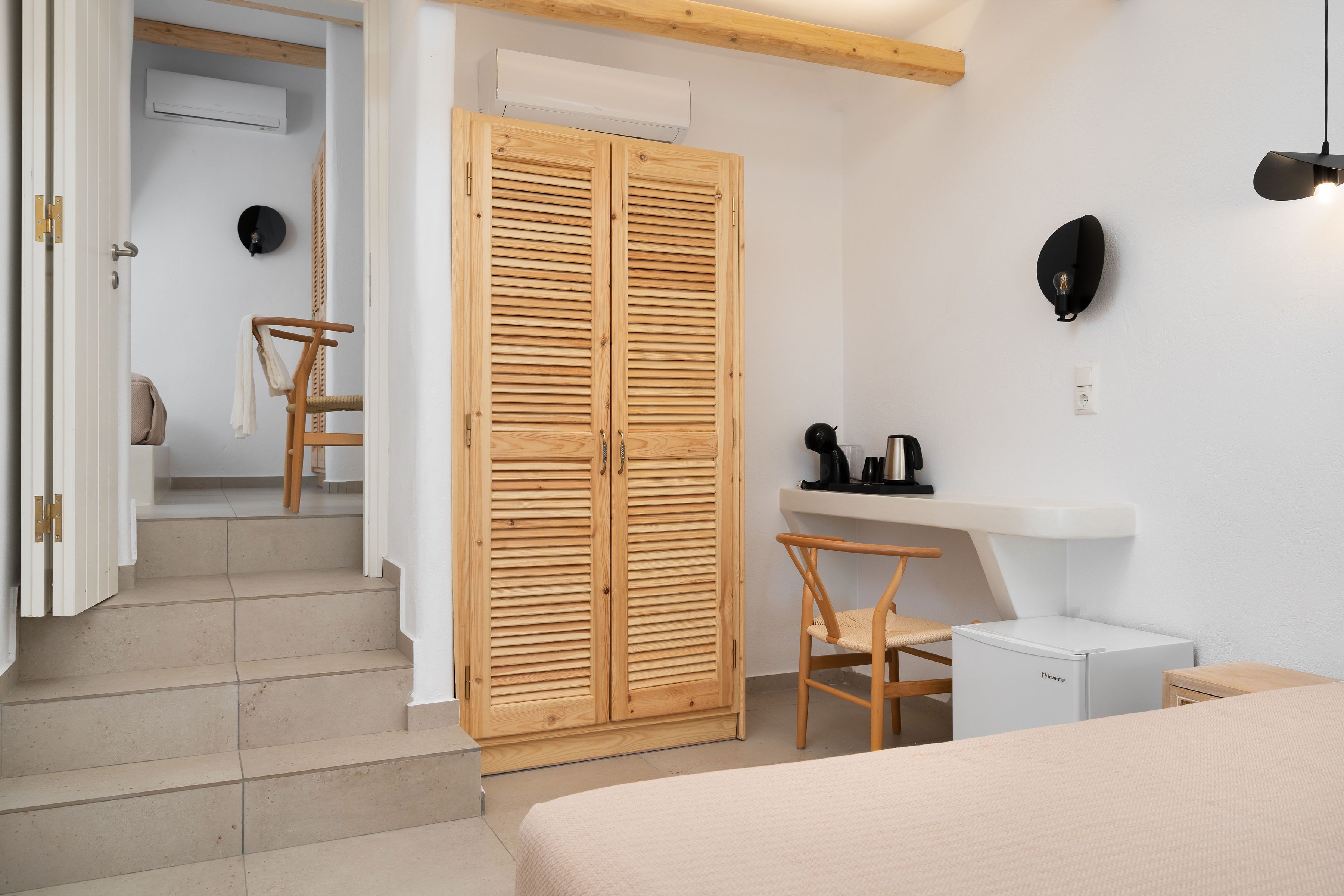 A bedroom with a bed, a wooden wardrobe, a small desk with a chair, and a white radiator.