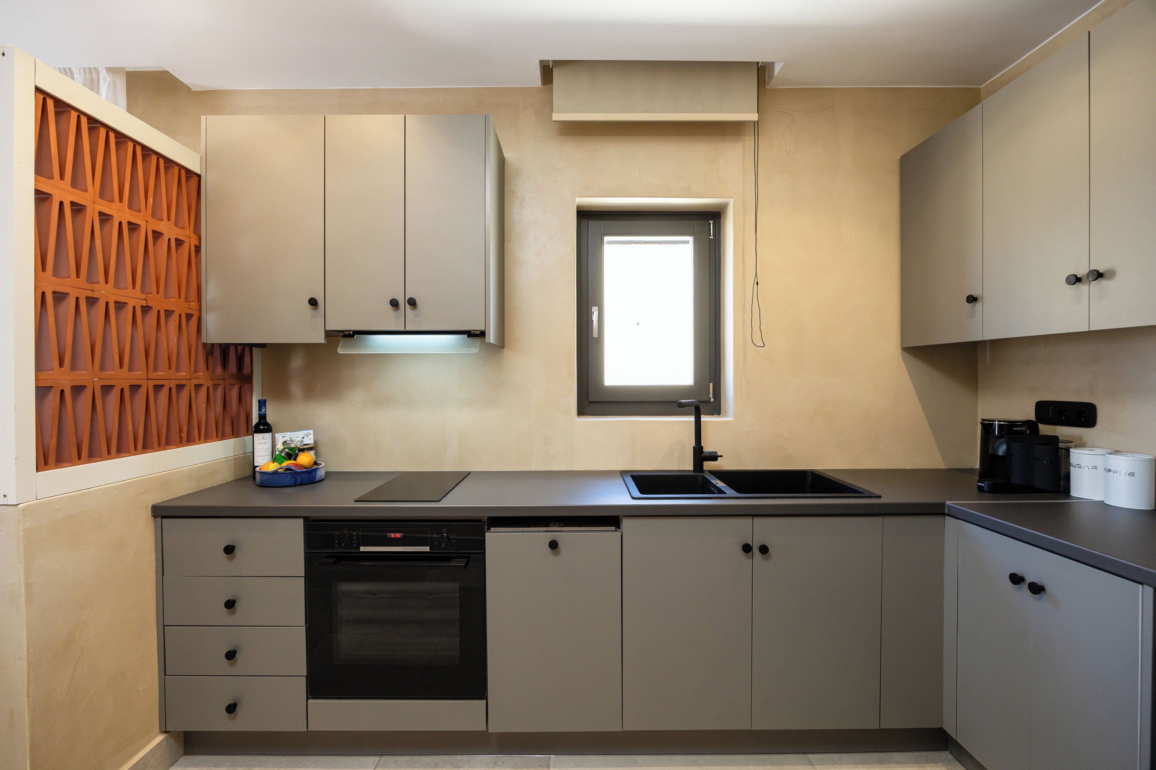 A modern kitchen with a built-in dishwasher, a coffee machine, and a window above the sink.