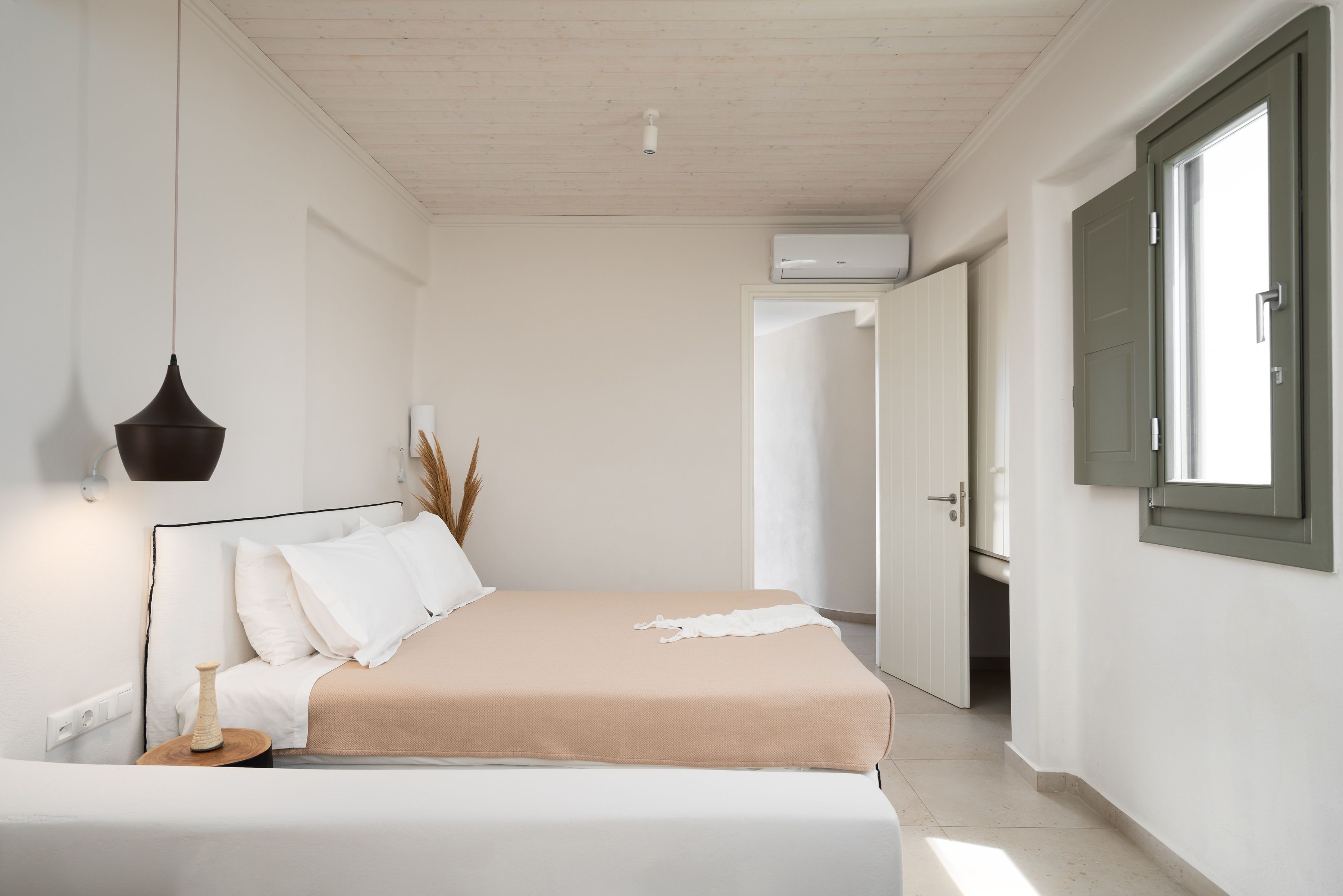 A minimalist bedroom with a bed, bedside table, and a hanging light fixture.