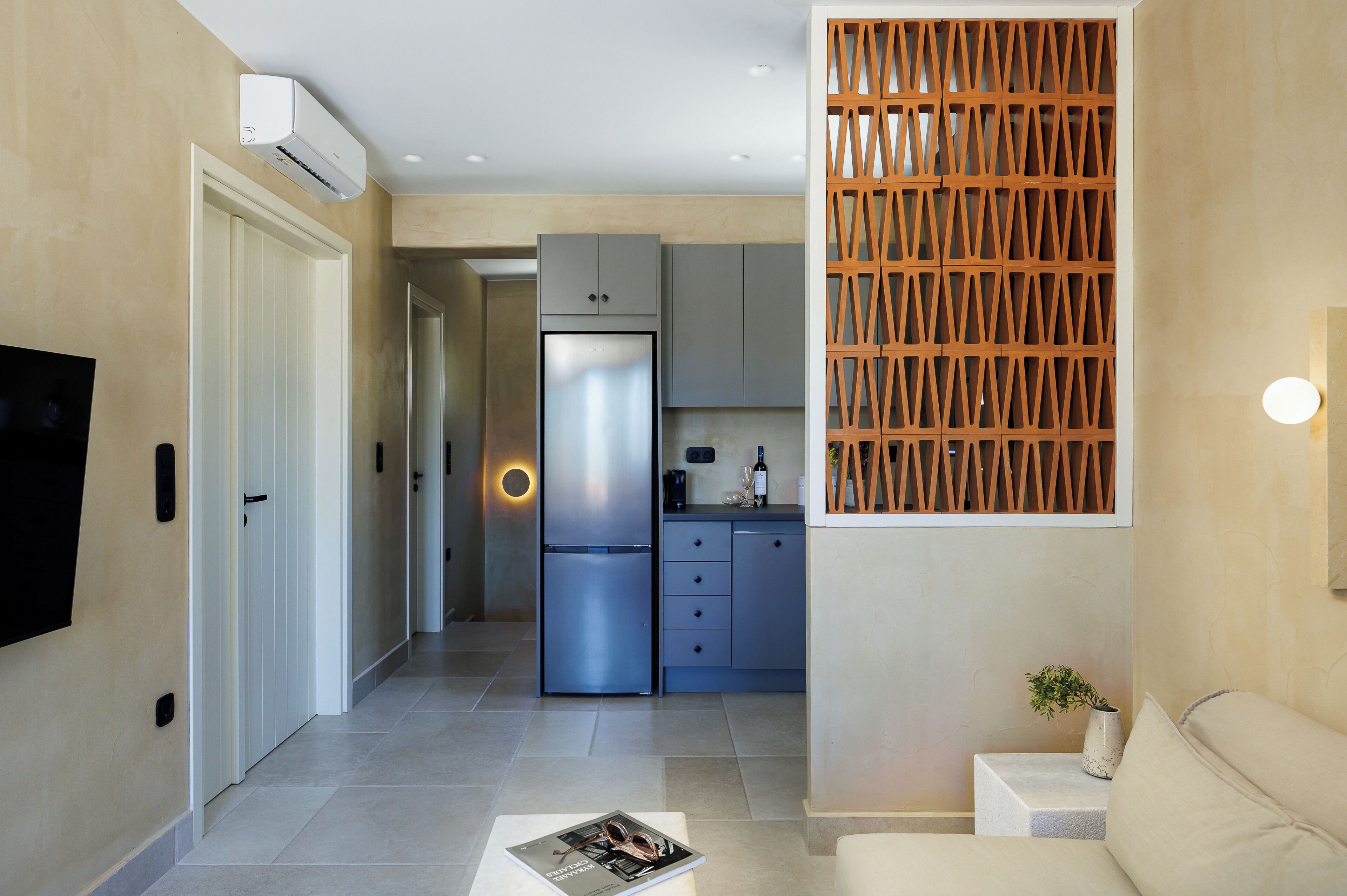 A modern kitchen with a built-in refrigerator, a wooden partition, and a dining area with a table and chairs.
