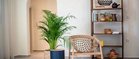A room with a wooden chair, a potted plant, a bookshelf, and a hanging light fixture.