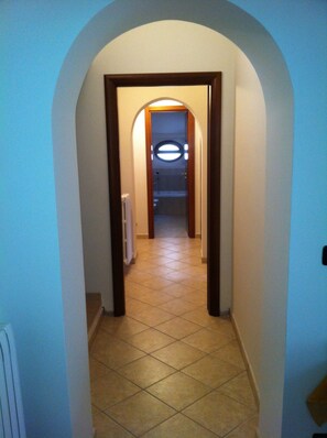 A narrow hallway with a tiled floor and a wooden door frame. - The Maze B&B (Vibo Valentia)