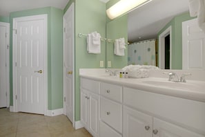 A bathroom with a white vanity, a large mirror, and a shower curtain.