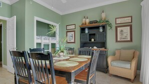 Un comedor con una mesa y sillas de madera, un sofá de mimbre y un aparador con objetos decorativos.