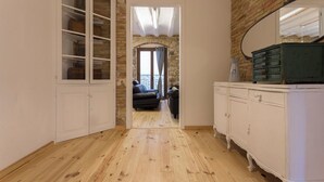 Een smalle gang met houten vloer, een witte kast en een spiegelkast.