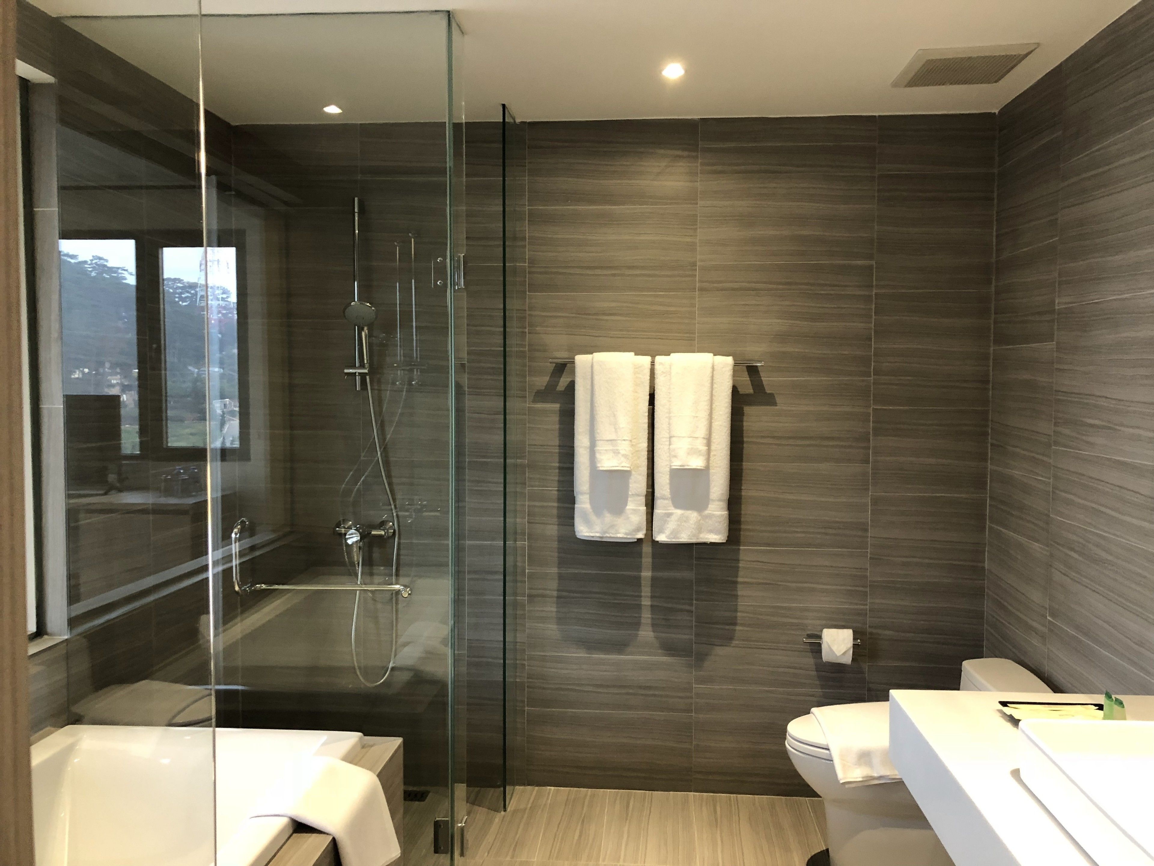Un baño moderno con ducha de vidrio, bañera y retrete.