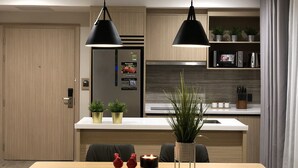 A modern kitchen with wooden cabinets, a built-in refrigerator, and pendant lighting. - The Luxe Hotel Da Lat (Xuan Huong - Da Lat)