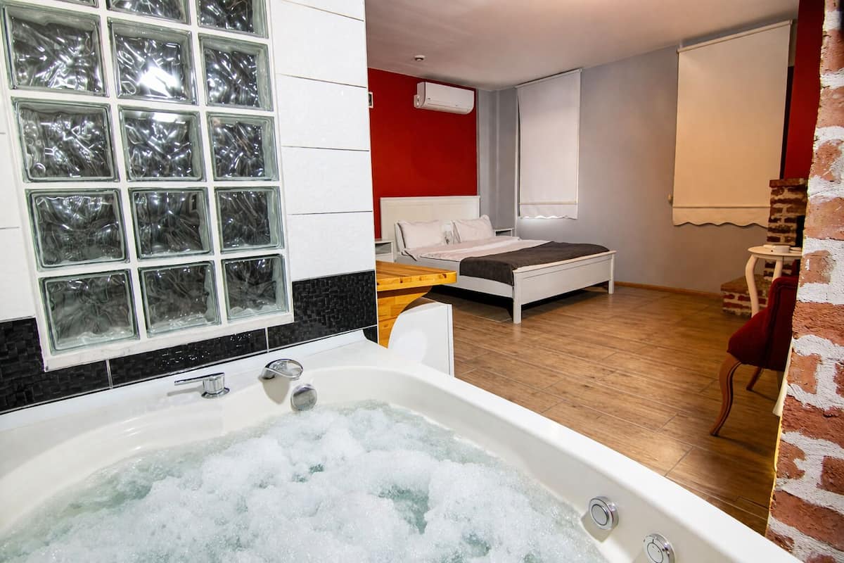 Een moderne slaapkamer met een groot bad, een bed en een rode accentmuur.