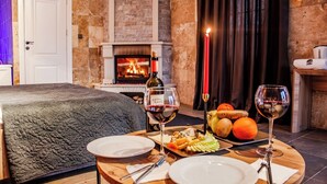 Una habitación acogedora con chimenea, una cama, una mesa de comedor con platos, vasos y una botella de vino.