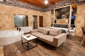 A room with a large bathtub, a sofa, a small table, and a bed. - 216 North Hotel & Wellness-Spa (Sile)