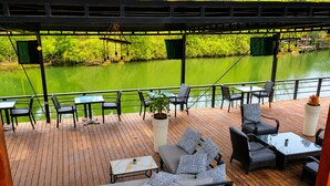 A wooden deck with outdoor seating, a view of a river, and a pergola structure.