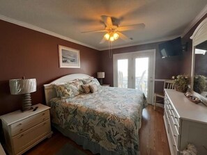 A bedroom with a bed, dresser, ceiling fan, and a door leading to a balcony. - Boston Commons 101 3 Bedroom Condo by RedAwning (Surfside Beach)