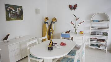 A modern, well-lit room with a white dining table, chairs, a bookshelf, and a butterfly decoration on the wall.