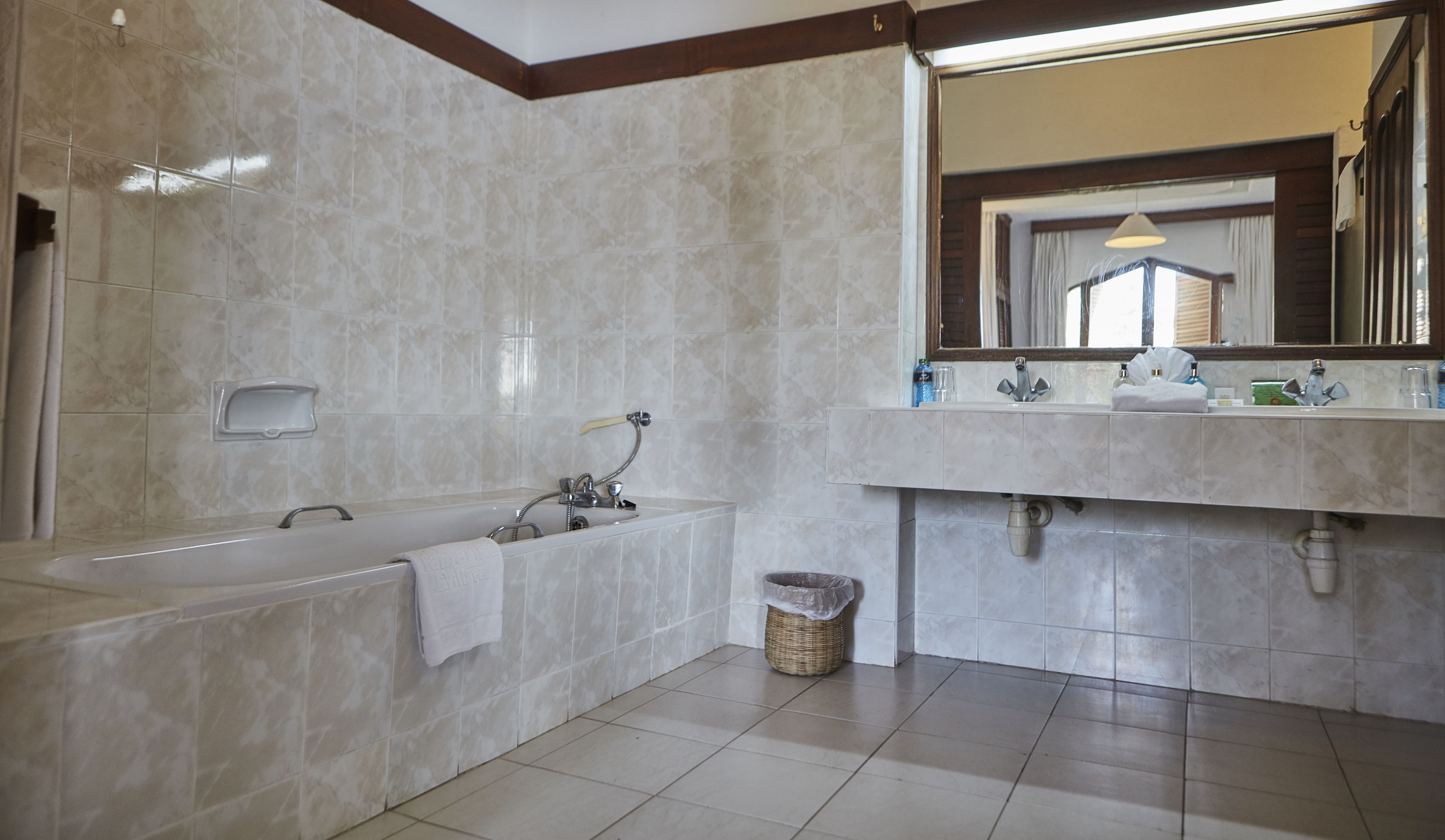 A modern bathroom with a bathtub, a large mirror, and a sink.