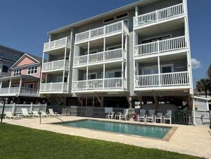 A multi-story building with balconies, a swimming pool, and outdoor seating. - Surfside By The Sea Ii 103 2 Bedroom Condo by RedAwning (Surfside Beach)