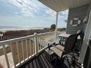 A covered porch with a view of the beach, a table, and a chair. - Surfside By The Sea Ii 103 2 Bedroom Condo by RedAwning (Surfside Beach)