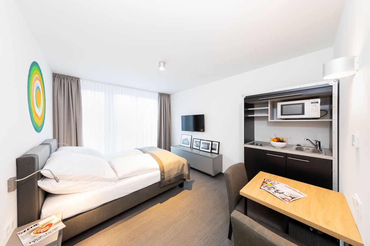 Una habitación de hotel moderna con una cama, un escritorio pequeño, un microondas y un televisor.