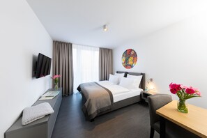 A modern hotel room with a bed, bedside table, chair, and a small desk. - Boardinghouse St.Pauli (Hamburg)