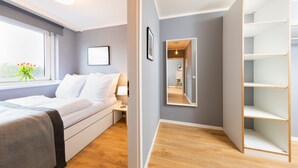 Un dormitorio moderno con cama, mesita de noche y ventana con vistas.