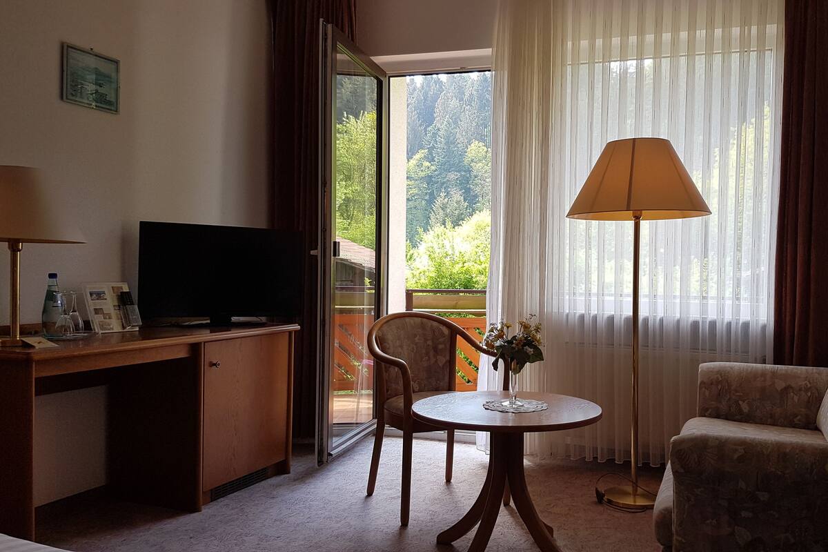 Een hotelkamer met een bureau, televisie, stoel en een bank.