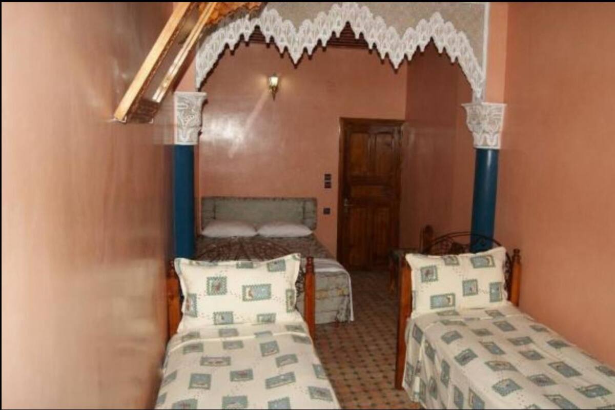 A room with two single beds, a wooden door, and a patterned wall.