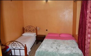 A small bedroom with two beds, one with a metal frame and the other with a wooden frame. - Hotel Jardin Public (Fes)
