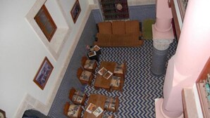 Ein Zimmer mit einem gemusterten Boden, einer Sofagarnitur und einem kleinen Tisch mit Stuhl.