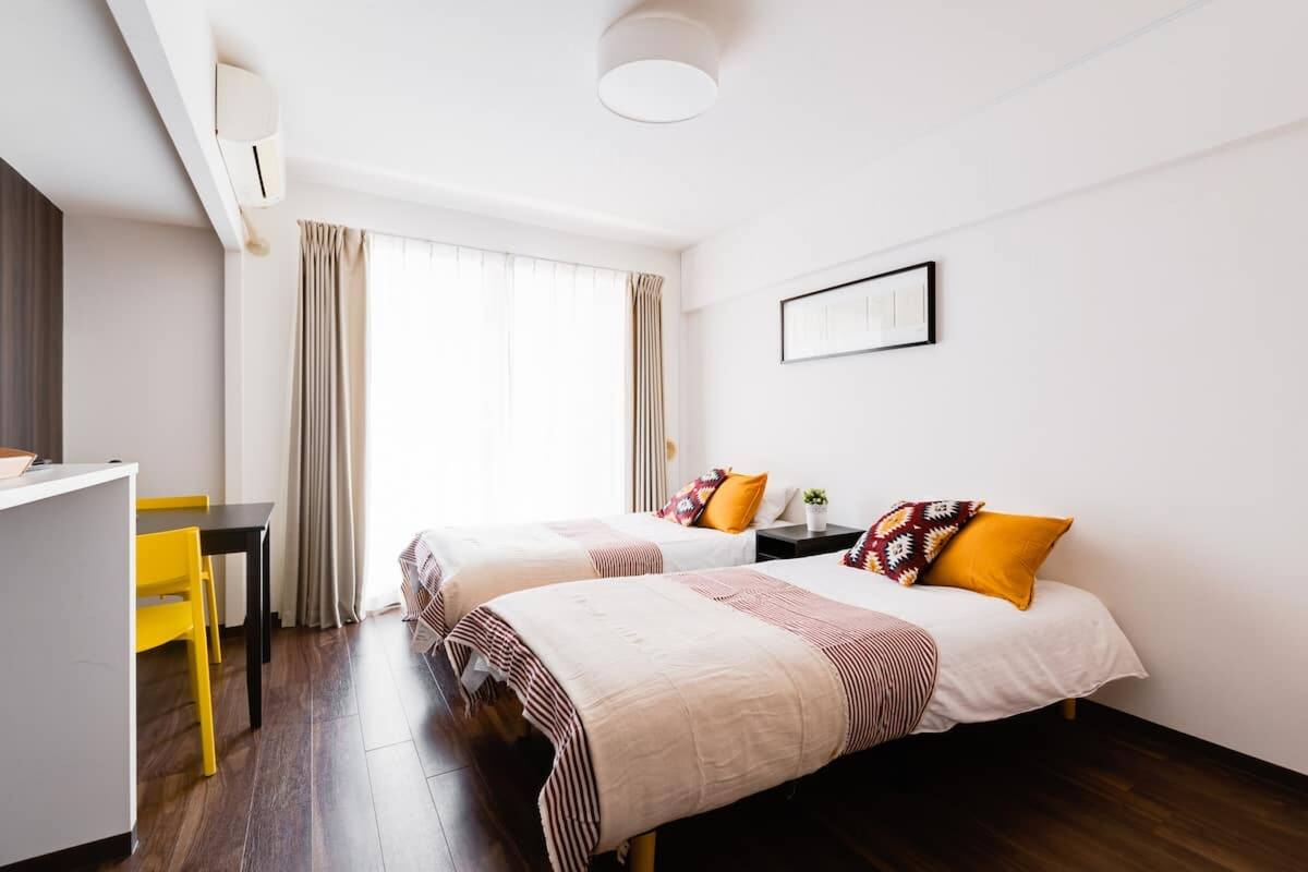 Quarto de hotel com duas camas, uma mesa e uma cadeira.