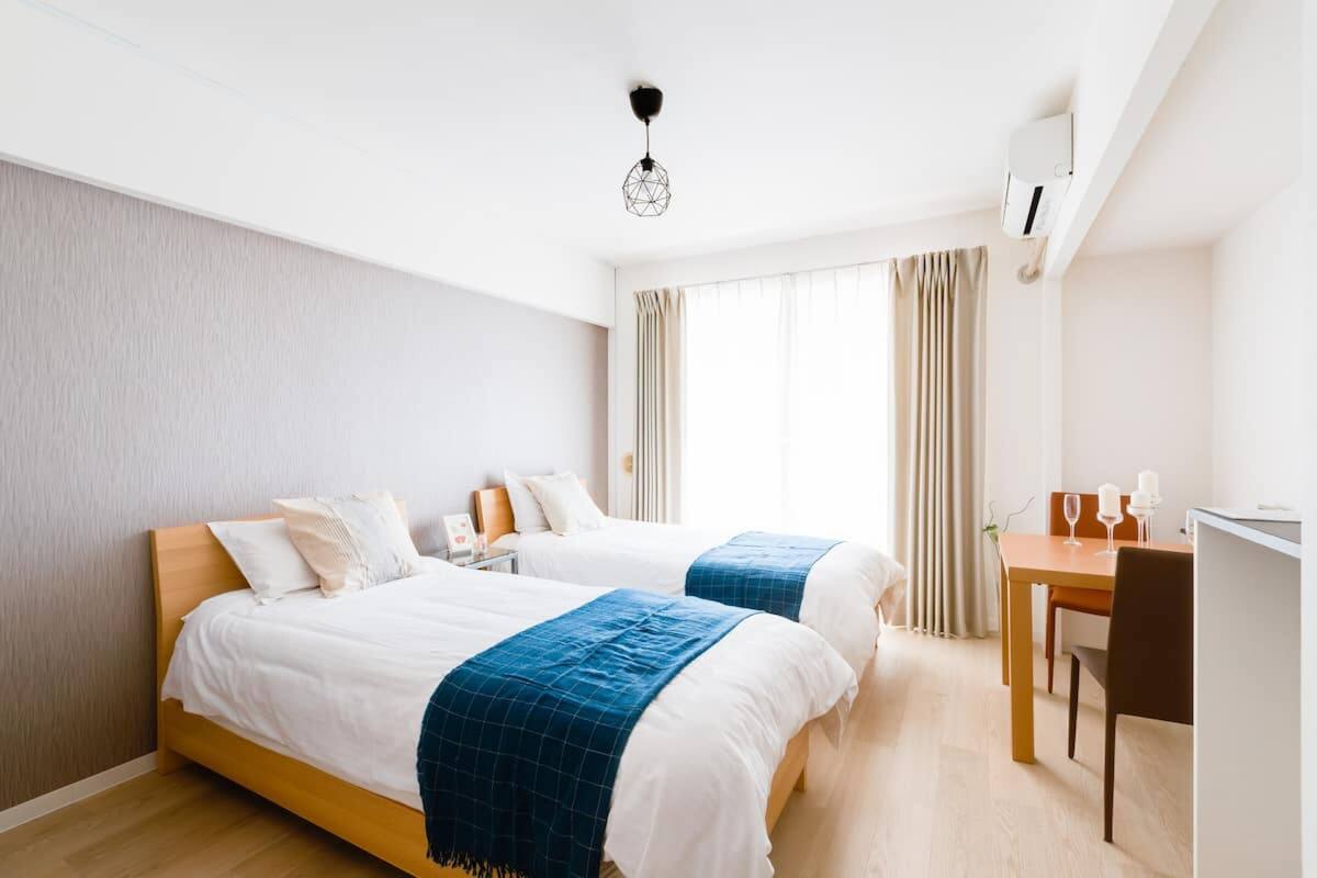 Quarto de hotel com duas camas, uma escrivaninha e uma cadeira.