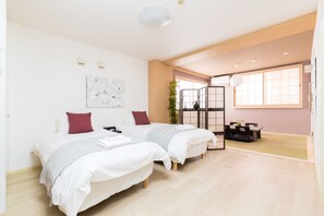 A modern hotel room with two beds, a dining area, and a large window providing natural light. - Guest House MIYABI (Kyoto)
