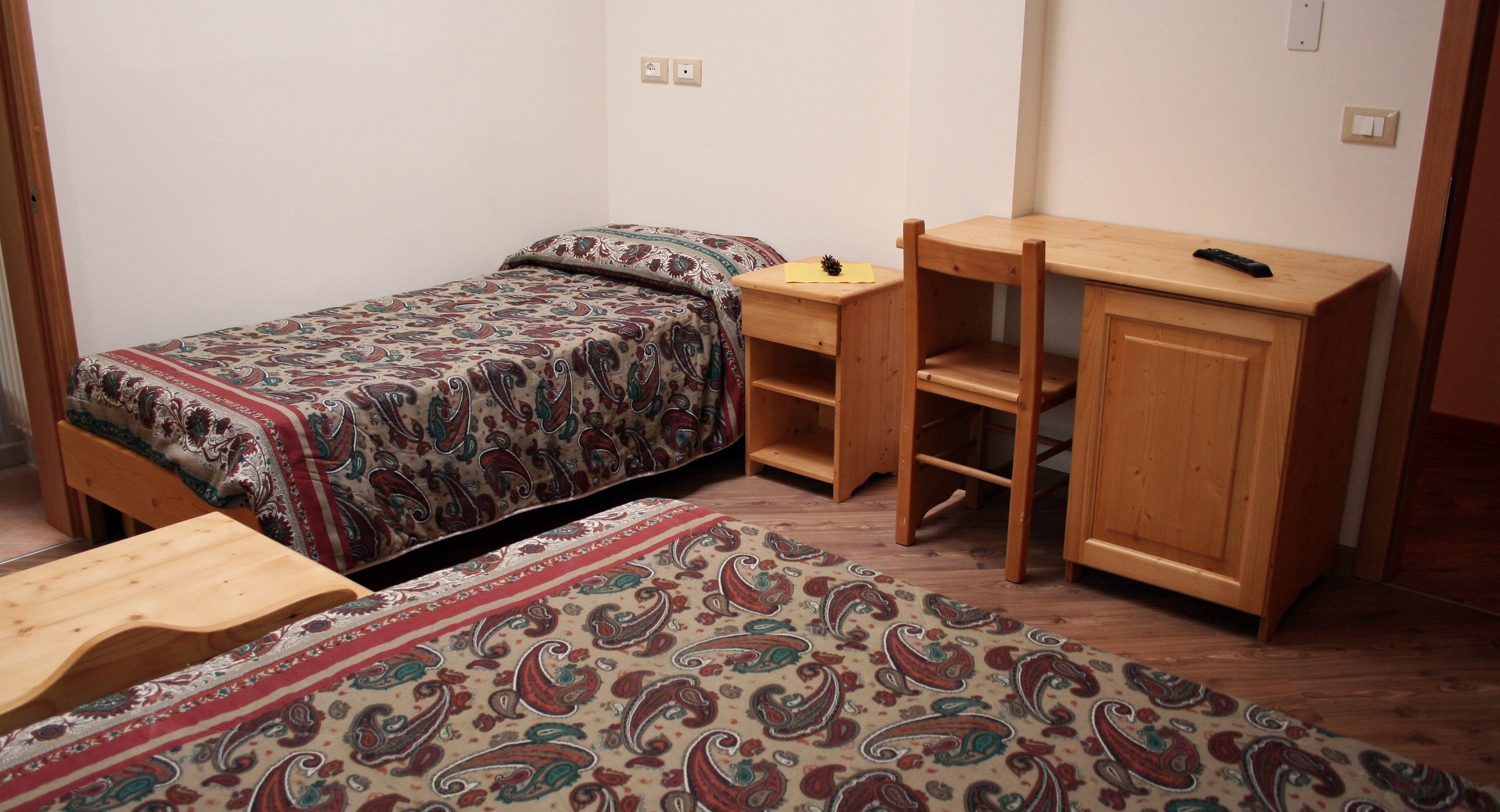 Ein kleines, gemütliches Zimmer mit Bett, Schreibtisch und Stuhl.