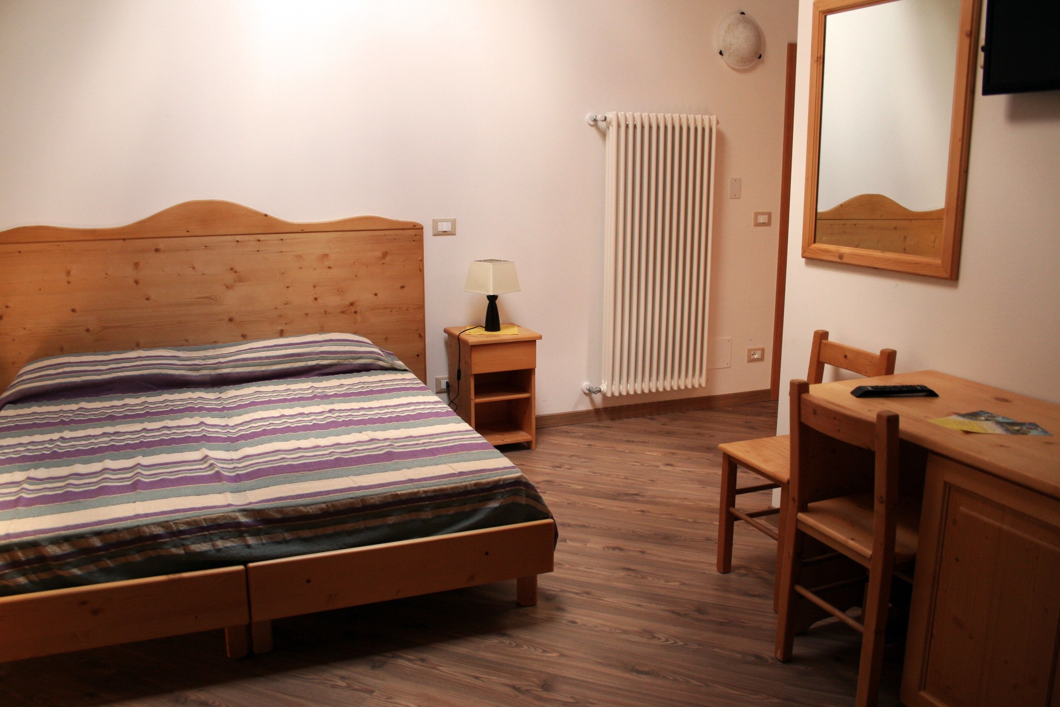 Une chambre à coucher avec un lit en bois, une table de chevet avec une lampe, un bureau en bois et une chaise.