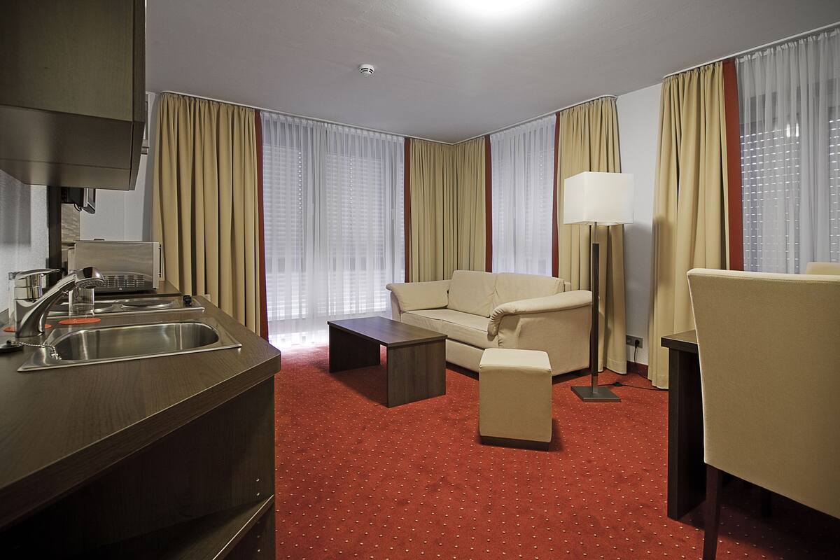 Une chambre d’hôtel équipée d’une kitchenette, d’un canapé, d’une table basse, d’une lampe et d’une chaise.