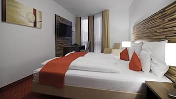 A hotel room with a large bed, a desk, a television, and a wooden headboard.