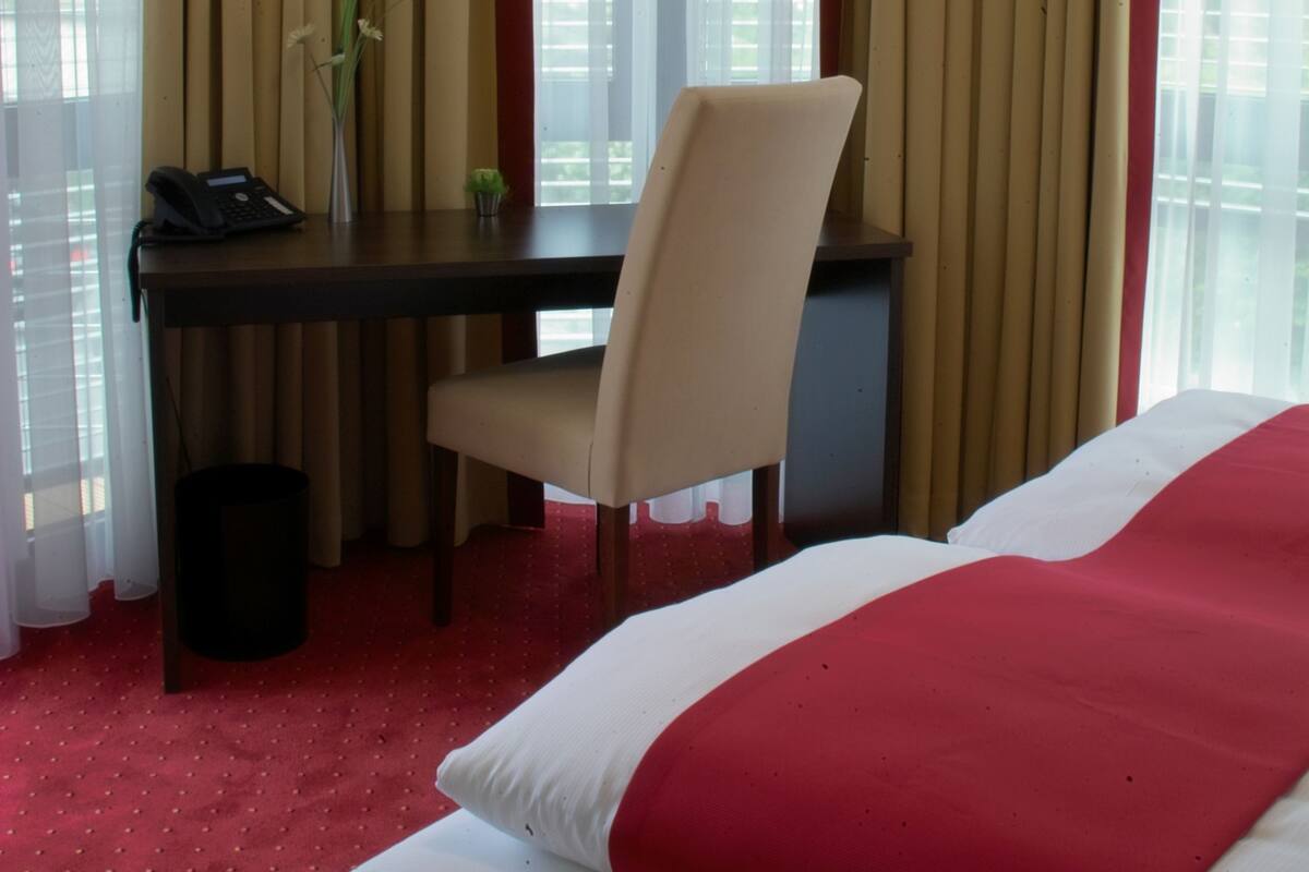 Une chambre d’hôtel équipée d’un lit, d’un bureau, d’une chaise et d’un téléphone.