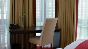 A hotel room with a bed, a desk, a chair, and a telephone.