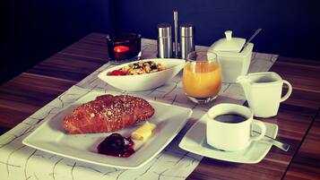 Desayuno con croissant, frutos rojos y jugo sobre una mesa.