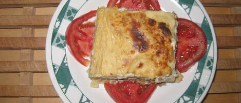 A slice of lasagna on a plate with tomato slices.