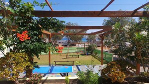 Un espacio al aire libre techado con mesa de ping pong, un columpio y una zona de juegos cercada.