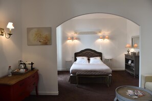 A bedroom with a large bed, a wooden dresser, a nightstand, and a reading chair. - Villa des Glycines (Thouars)