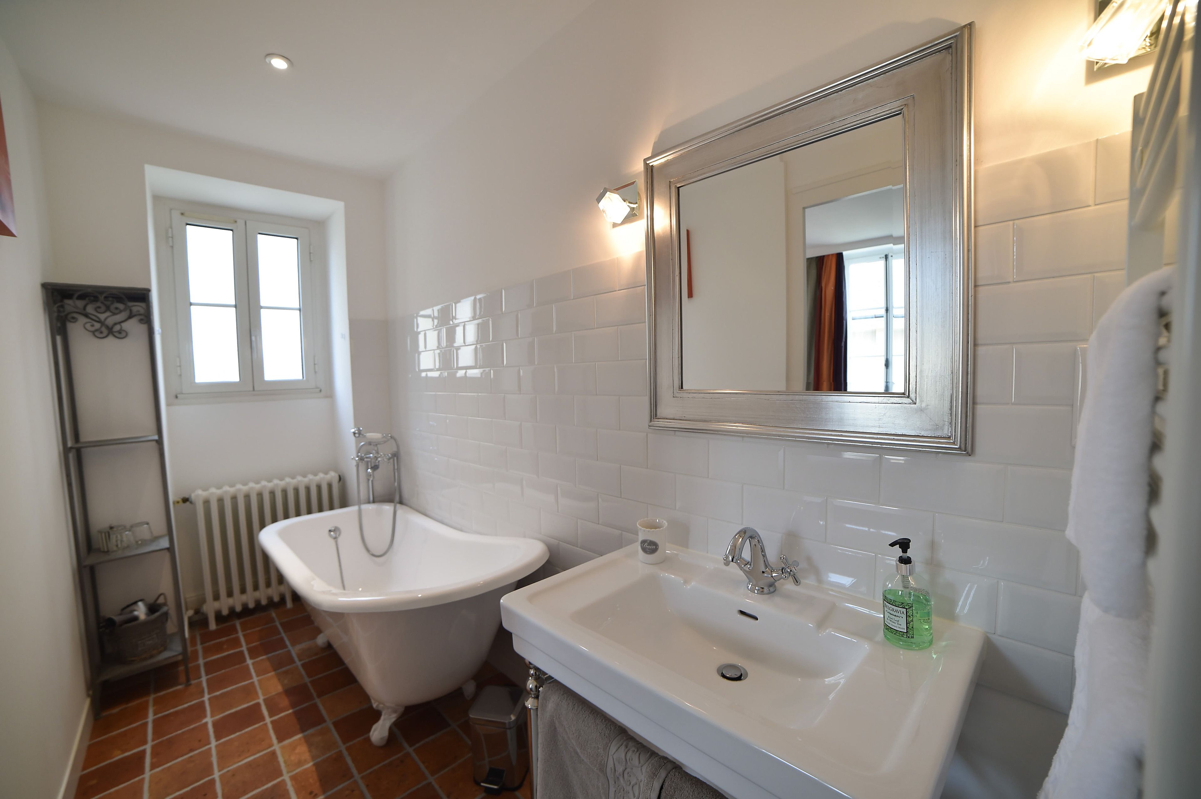 Une salle de bain avec une baignoire blanche, un lavabo et un grand miroir.
