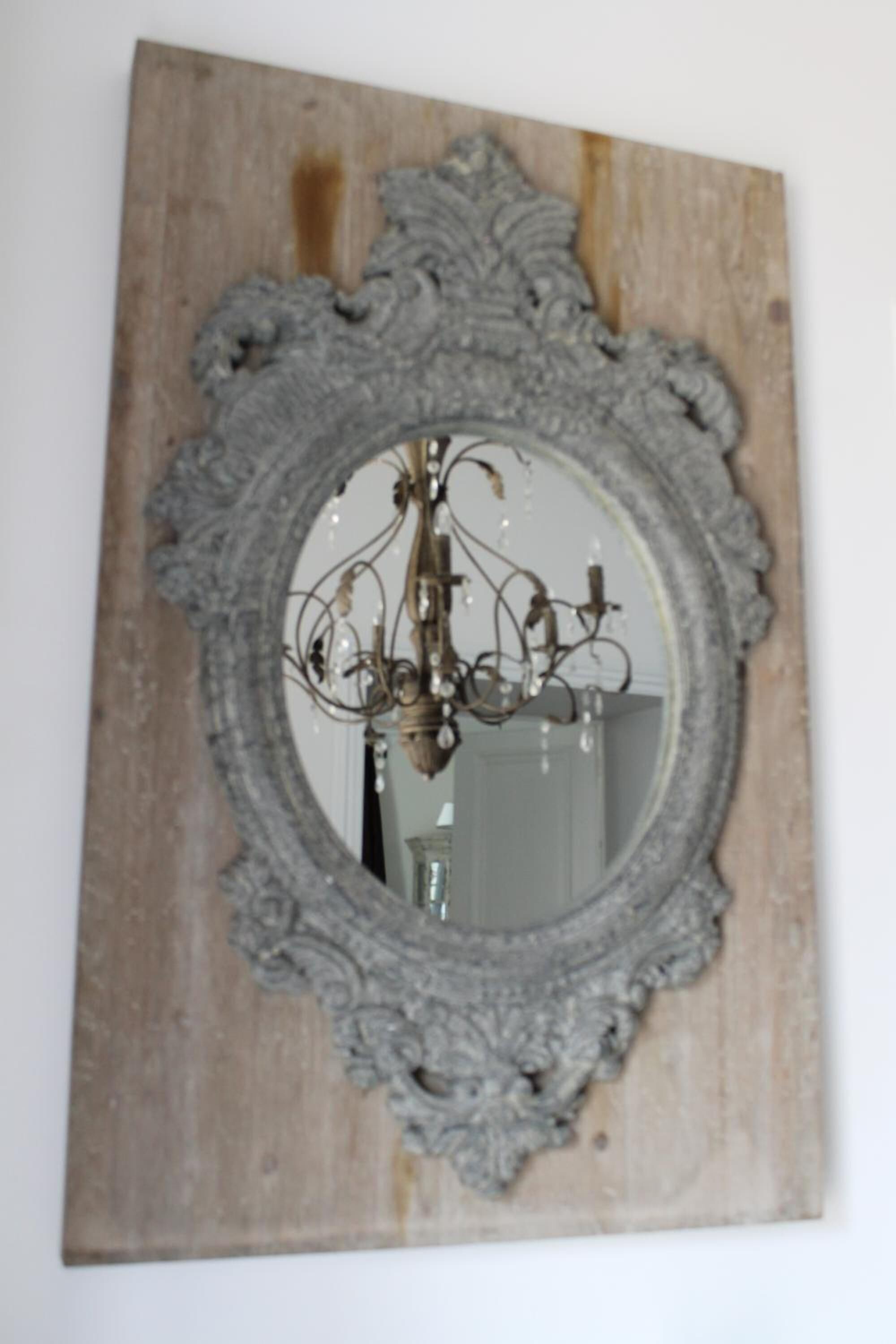 A mirror with an ornate frame mounted on a wooden wall.