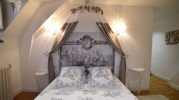 A bedroom with a canopy bed, ornate headboard, two bedside tables, and a radiator.