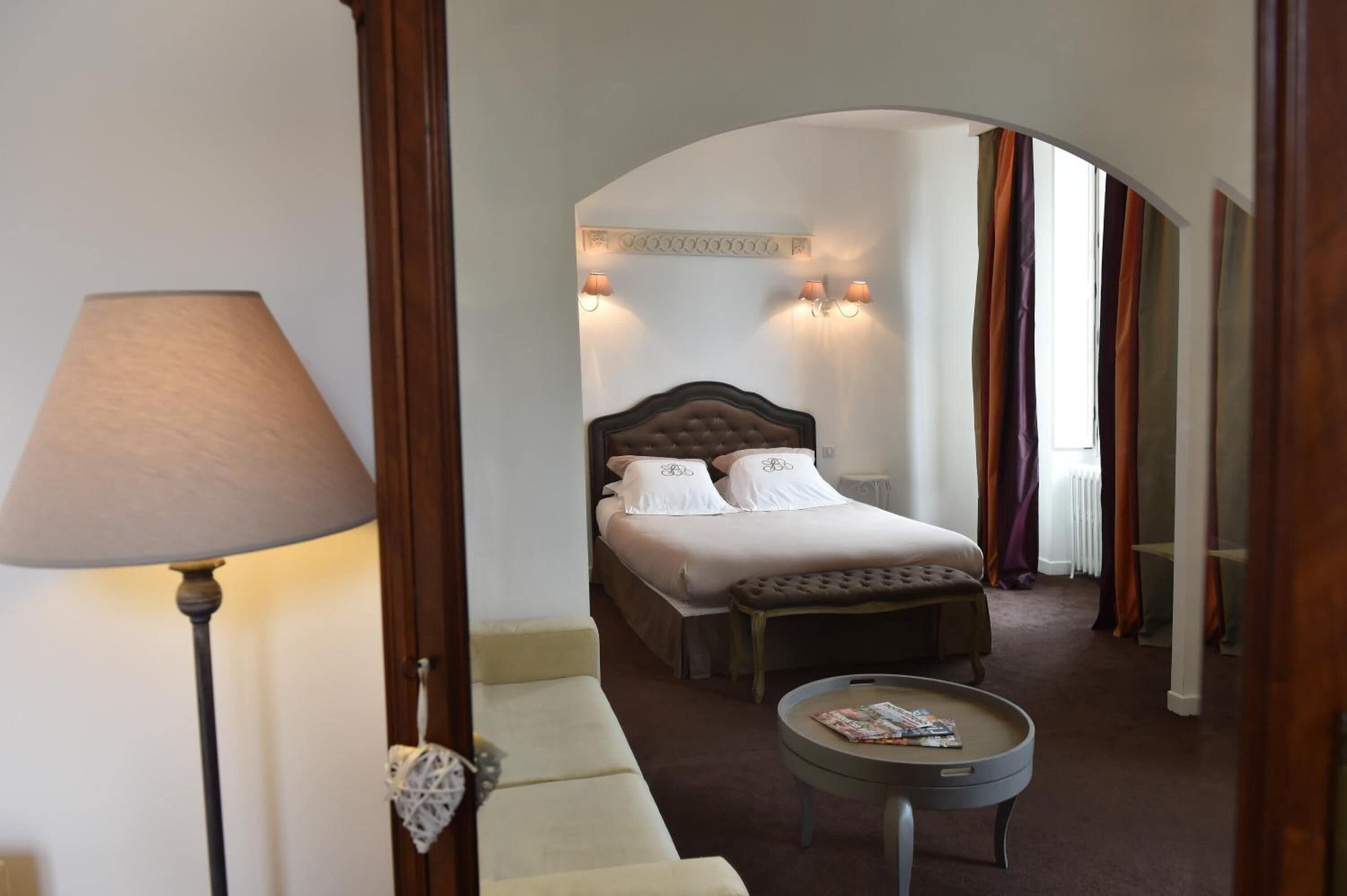 Une chambre d’hôtel avec un lit, un canapé, une lampe et une petite table.